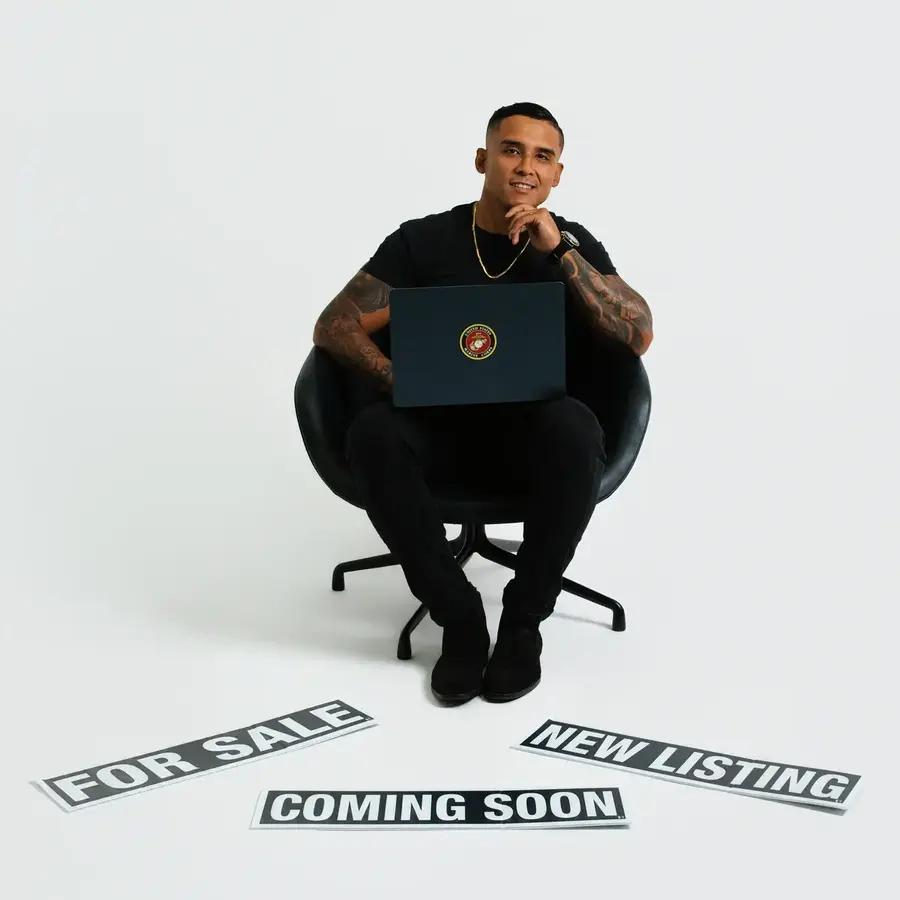 Freddy Alban seated with a laptop and real estate signs